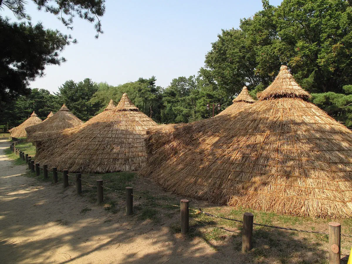 A row of reconstructed Neolithic pit-houses with conical thatched roofs at the Seoul Amsa-dong Prehistoric Settlement Site