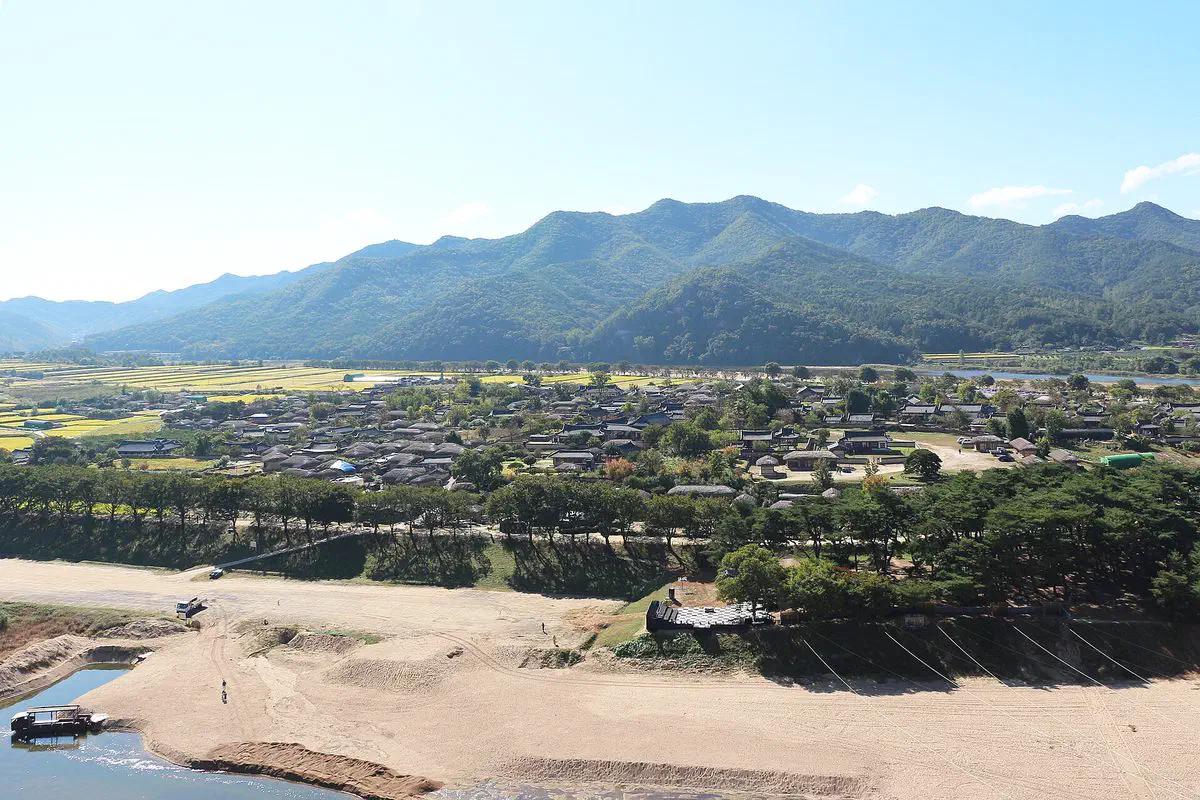 Aerial view of Hahoe Village, its thatched and tiled hanok cupped inside the horseshoe bend of the Nakdonggang, with a sandy riverbank and mountains behind