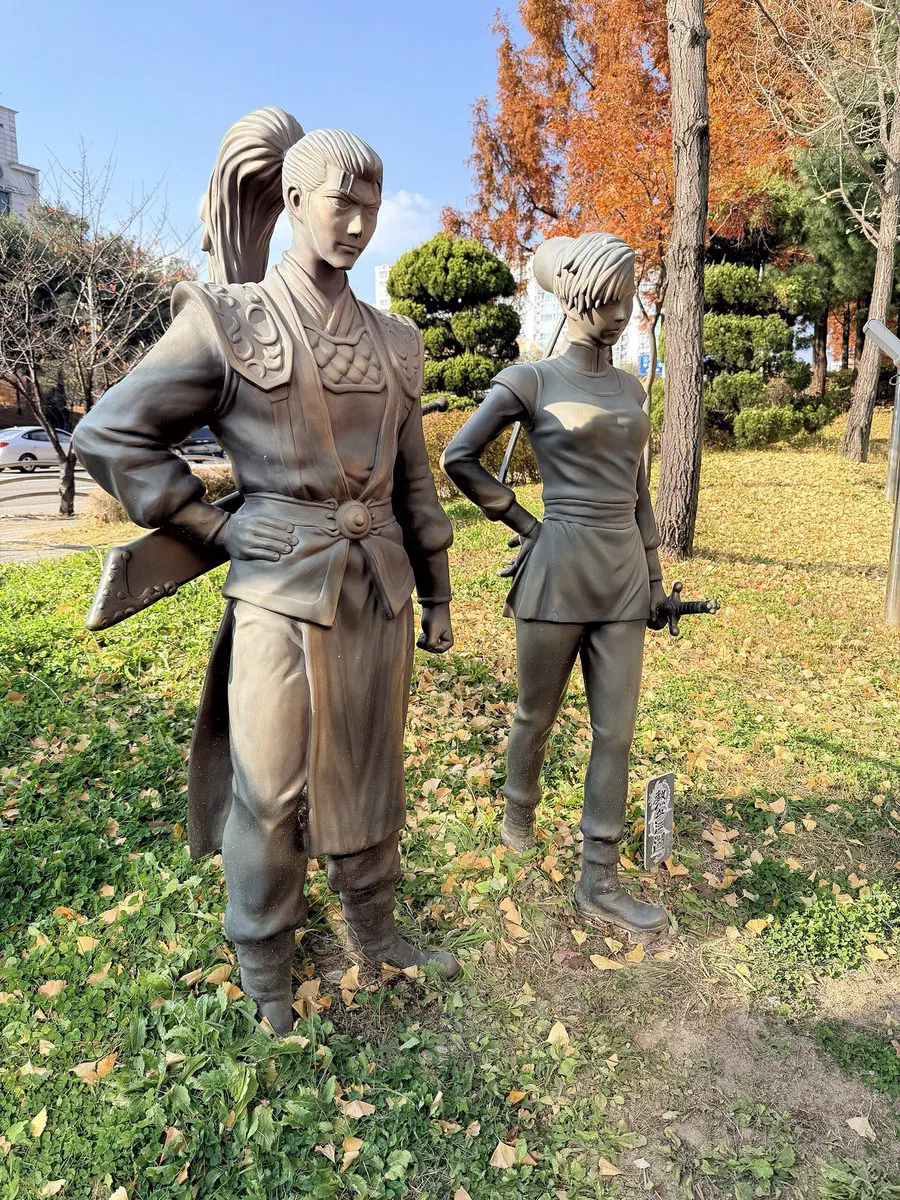 Bronze statues of two sword-carrying characters from Yeolhyeol Gangho, a long-running Korean manhwa, standing in the courtyard of the Korea Manhwa Museum in Bucheon