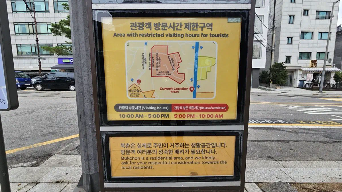 Official Jongno district signboard marking Bukchon's tourist-restricted zone, listing visiting hours of 10 AM to 5 PM and restricted hours from 5 PM to 10 AM