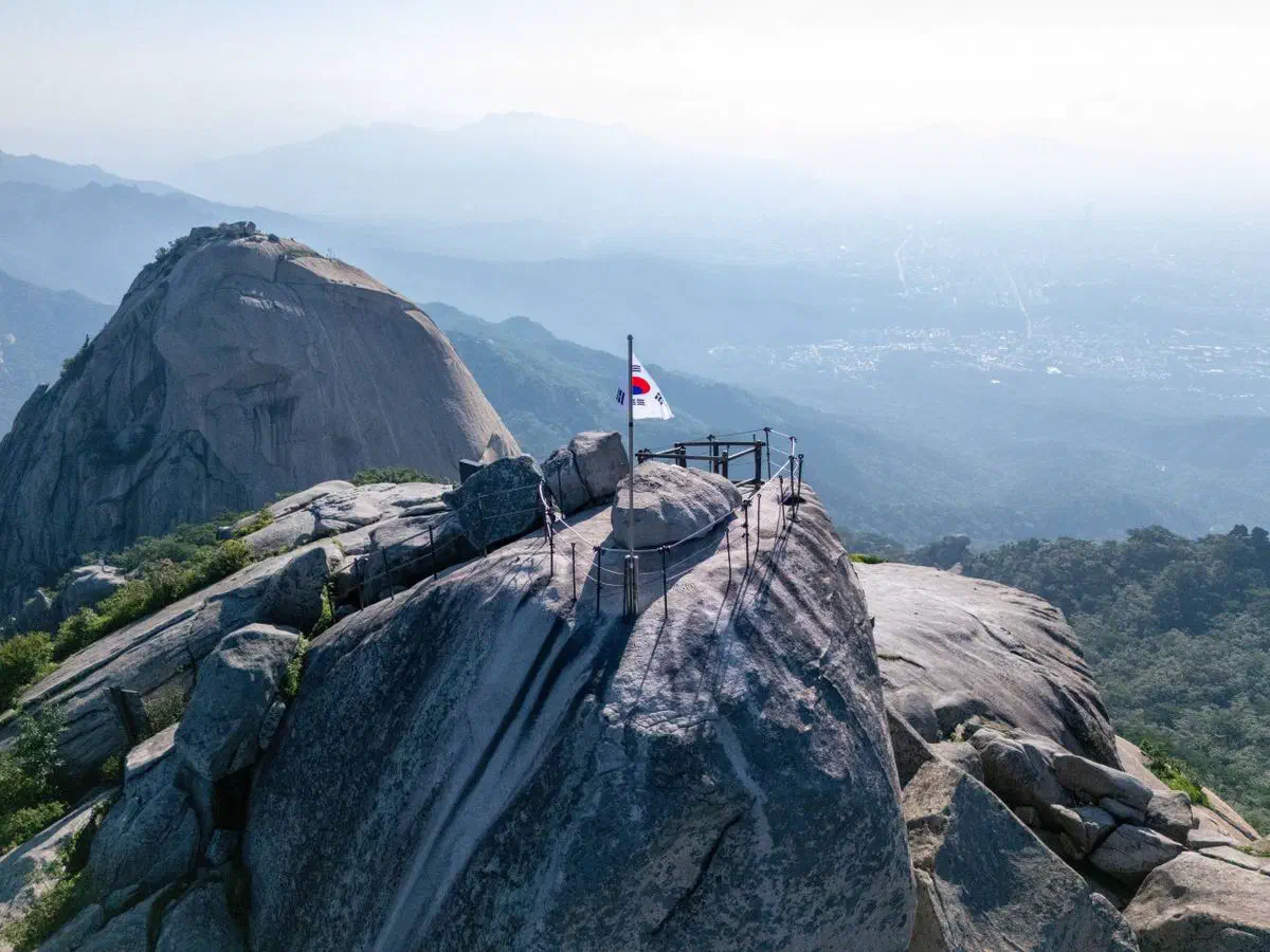 Aerial drone view of Bukhansan National Park's Baegundae course, granite peaks rising above the forested ridgeline