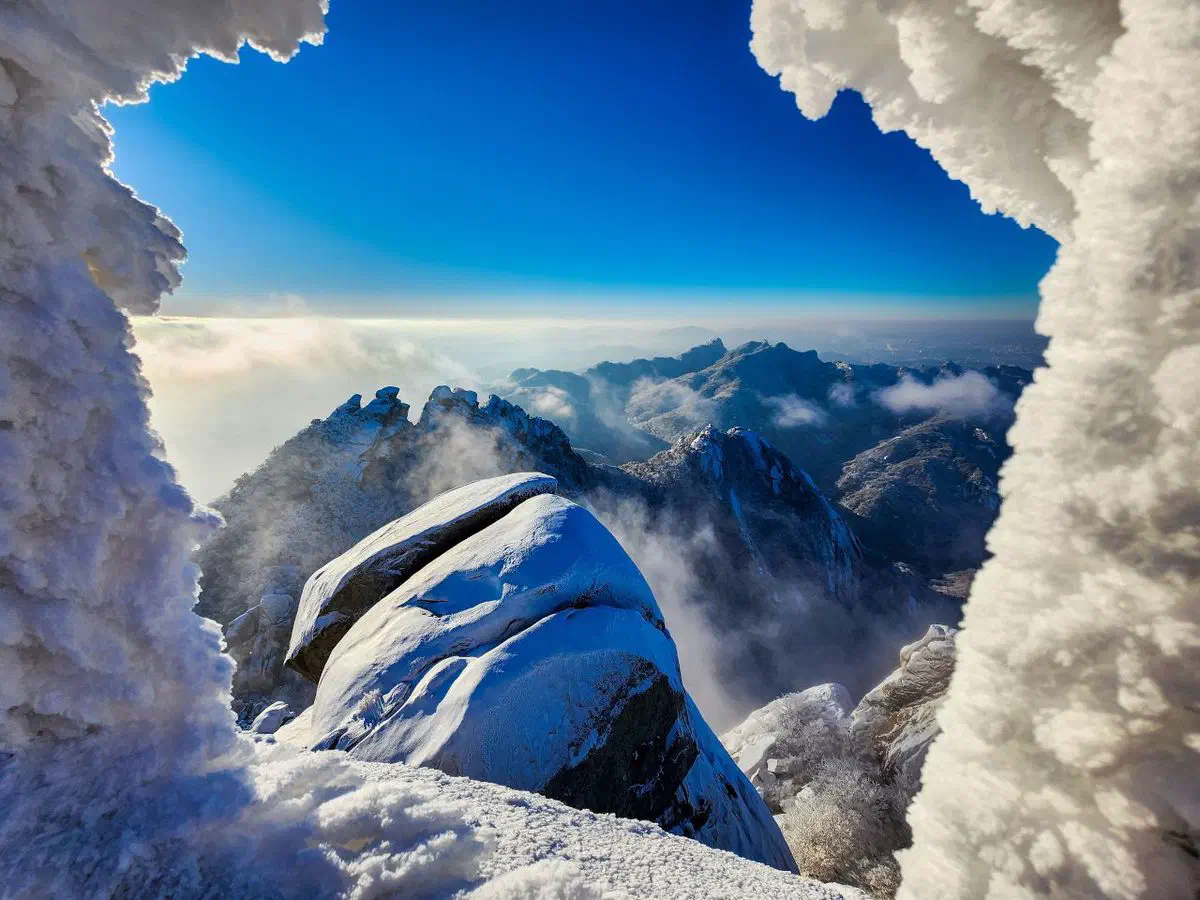 Bukhansan's granite ridgeline dusted with snow, mist rising between the peaks in winter