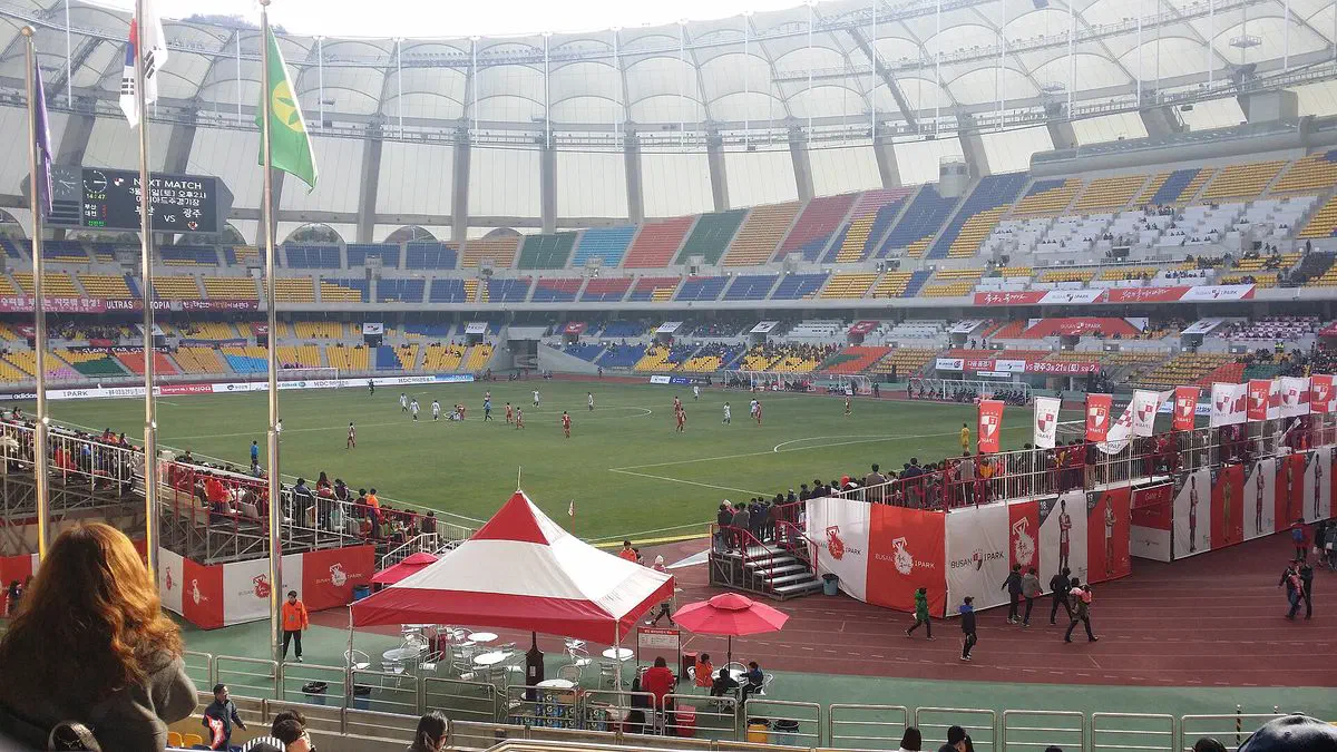 The seating bowl and field inside Busan Asiad Main Stadium during a football match, its retractable roof visible overhead