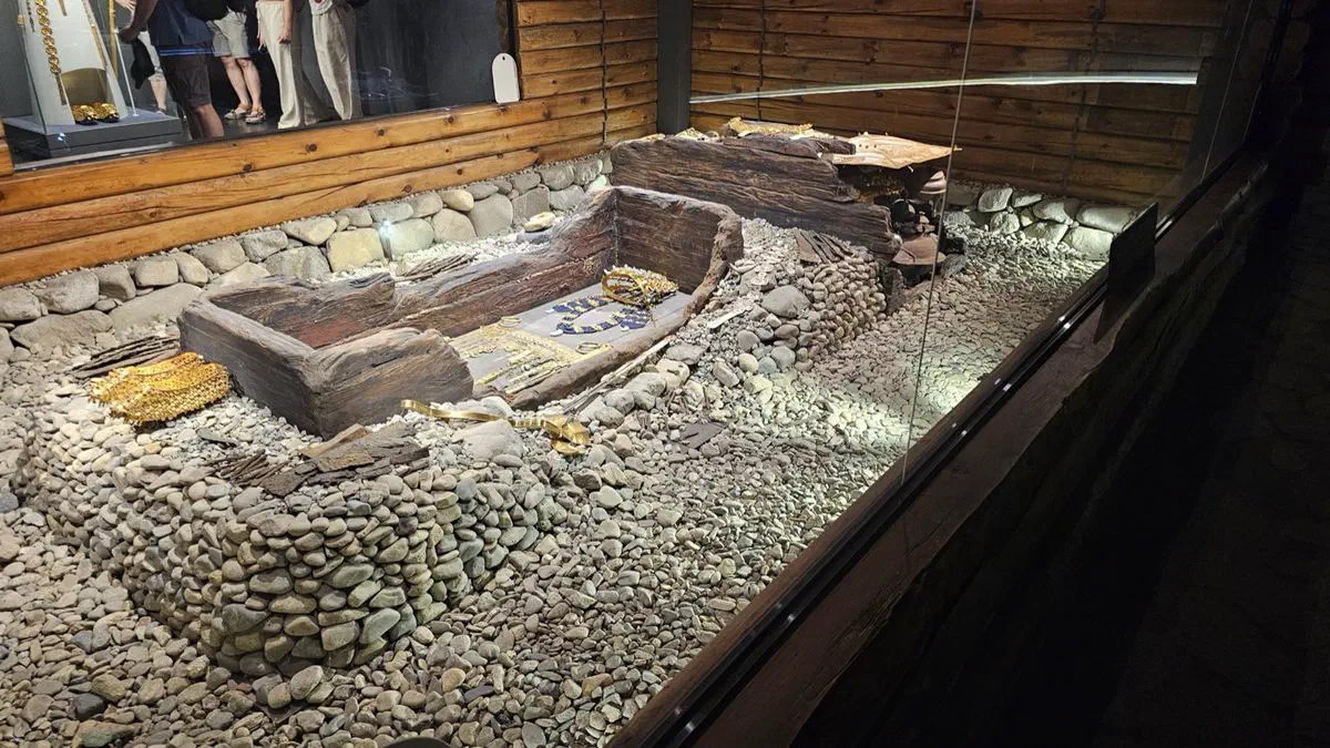 The reconstructed burial inside Cheonmachong — the wooden coffin with its gold crown and belt in place, packed around with river stones