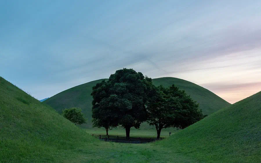 Grass-covered Silla royal tombs at sunset in Daereungwon Tumuli Park, in the middle of downtown Gyeongju