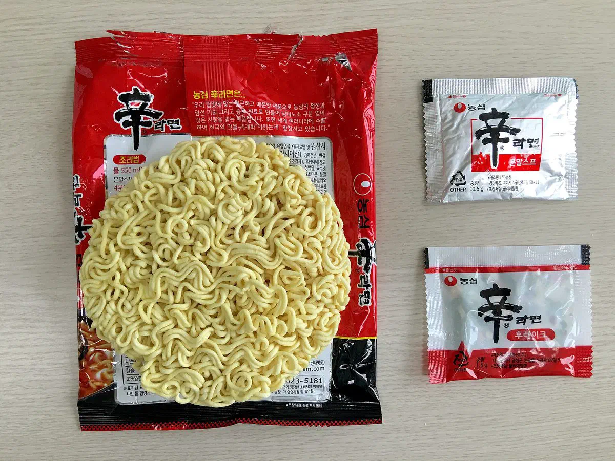 The dried noodle block and soup packet from inside a bag of Shin Ramyun, laid out side by side