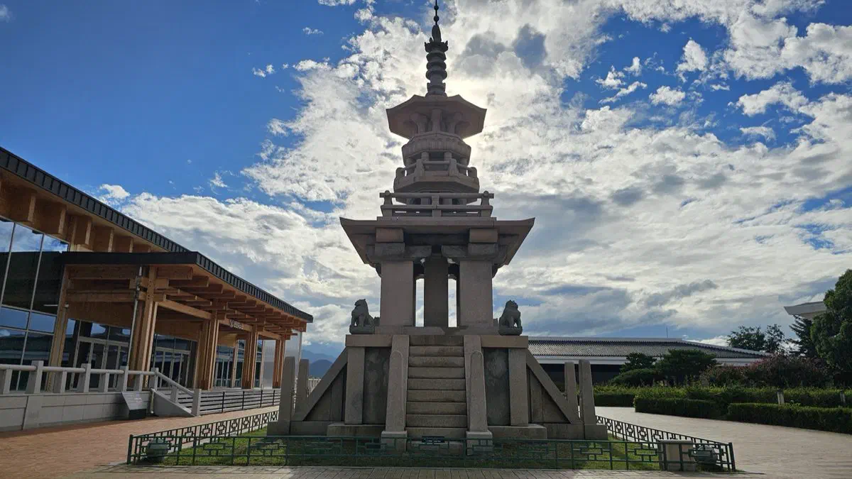 A stone pagoda and lantern outside the National Gyeongju Museum's wood-eaved entrance hall