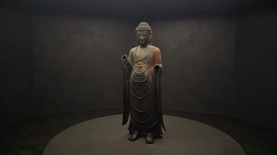 A stone Buddhist figure in a hooded robe, displayed at the National Gyeongju Museum