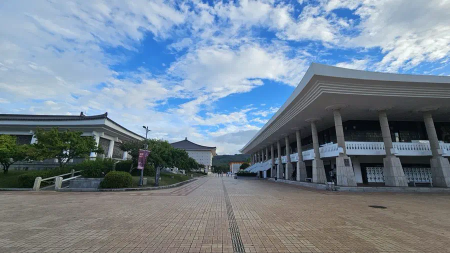 A brick walkway across the National Gyeongju Museum grounds under a blue sky