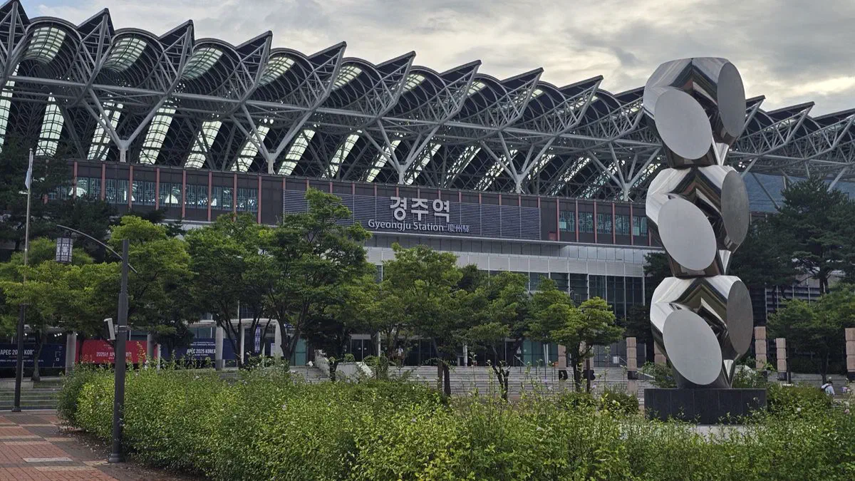 Gyeongju Station's glass-and-steel roof and a mirrored sculpture in the plaza garden out front, the station renamed from Singyeongju in 2023
