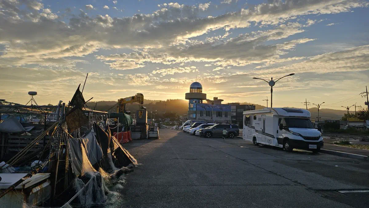 The road along Jeonchon Harbor at sunset, fishing gear drying at the water's edge
