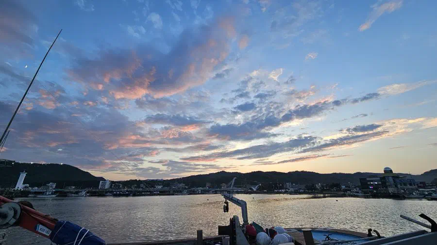 Sunset over the water at a Gyeongju coastal harbor, a boat silhouetted against it