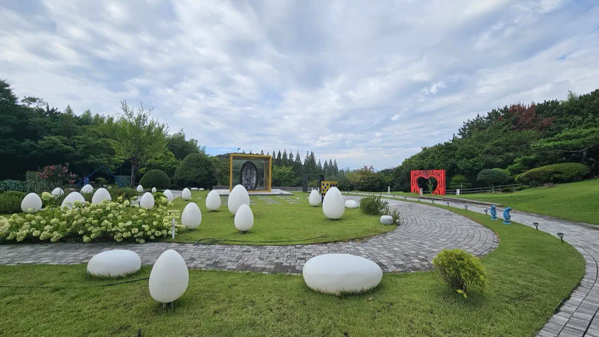 White egg-shaped stone sculptures scattered across the lawn of Kolon Hotel Gyeongju's garden, along a curving pathway