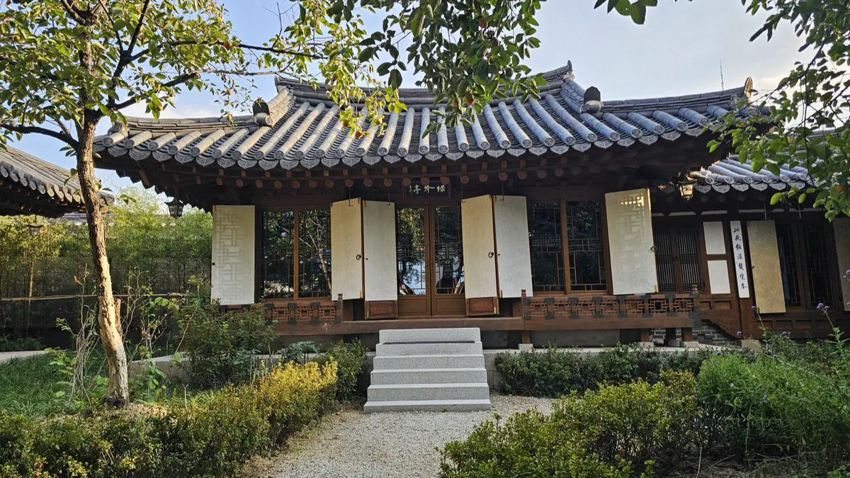 A low hanok annex with paper-covered shutters, gravel path and low hedges