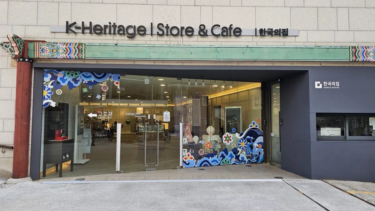 Storefront of the K-Heritage Store and Cafe at Korea House, with a dancheong-painted beam and wave-pattern window decals