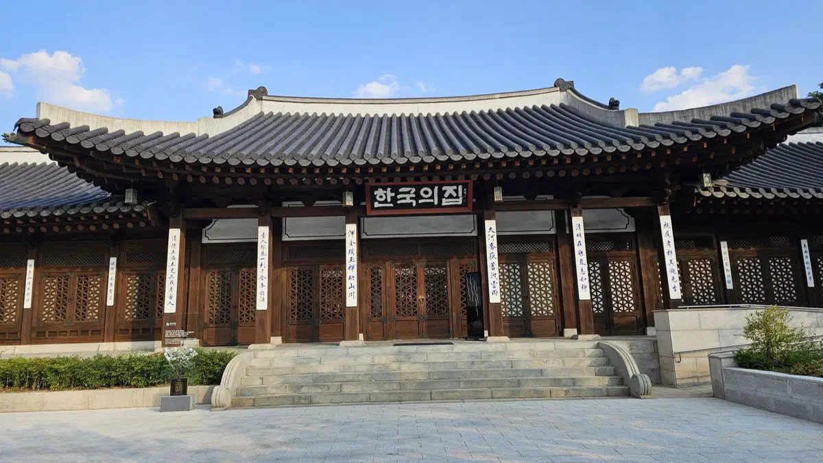 Front of Korea House's main hall, dark wooden lattice doors and a stone stair, vertical couplets on the pillars