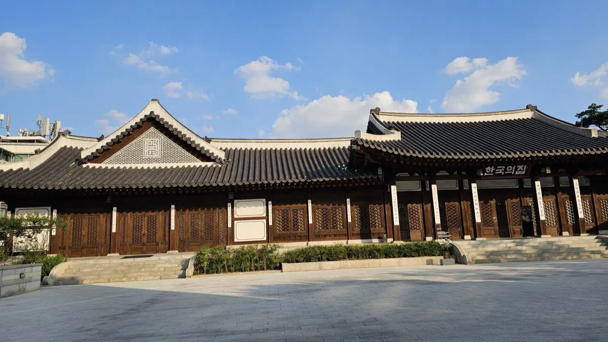 The long tiled roofline of Korea House's main hall under a blue sky