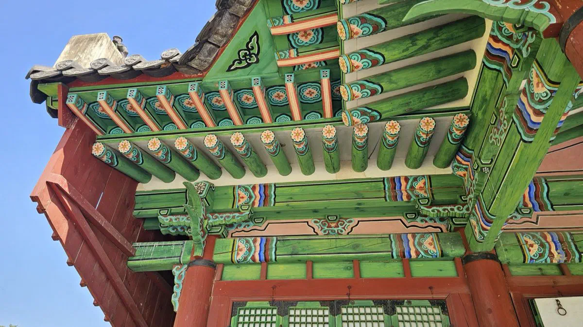 Looking up into the green, red and blue painted eaves of a ritual hall at Seooreung