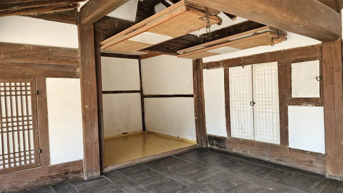 An empty wood-floored room with paper doors and a yellow oiled-paper floor inside the surviving tomb keeper's house