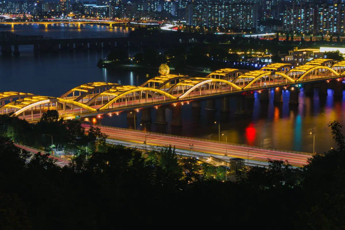 The Han River at night with its bridges lit up, the kind of skyline view Seoul Star City's café level looks out on