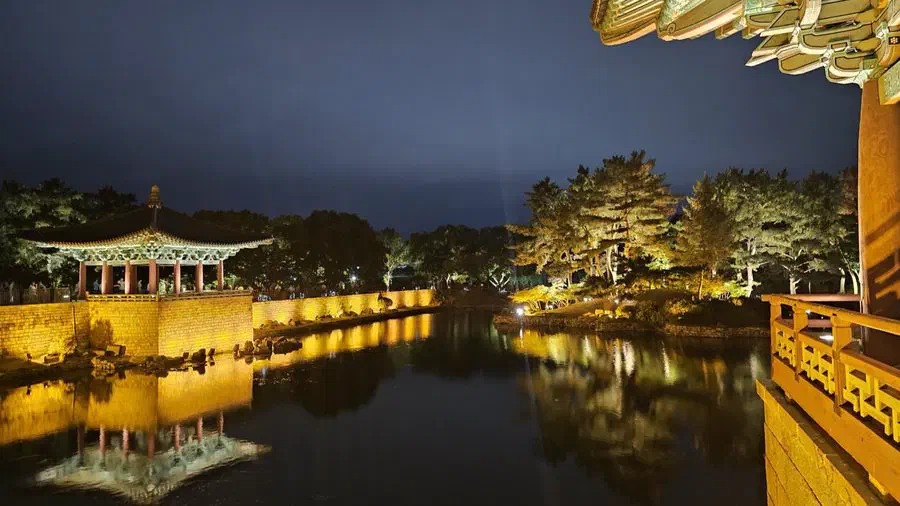 Donggung Palace's pavilions lit up at night, reflected in the still water of Wolji Pond in Gyeongju